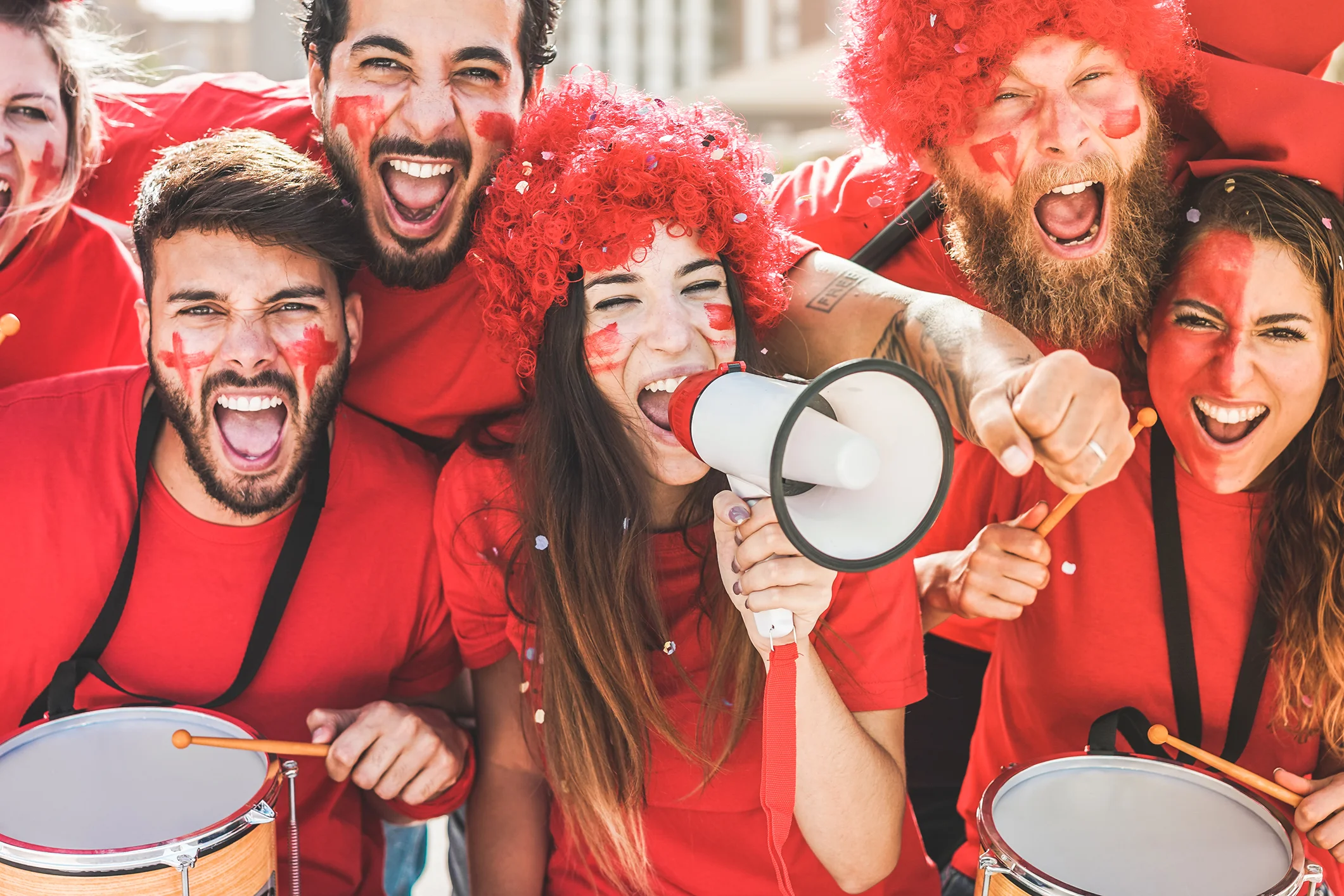 Red sport fans screaming while supporting their team out of the stadium - Football supporters having fun at competion event - Champions and winning concept - Focus on center girl face