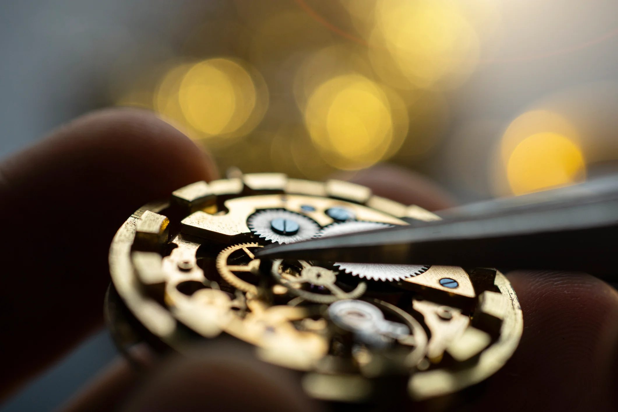 Black and white closeup photograph of a watchmaker examining the dial of a watch
